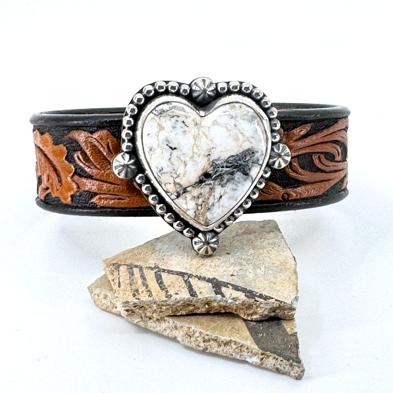Leather cuff bracelet with White Buffalo heart-shaped stone on floral western leather belt