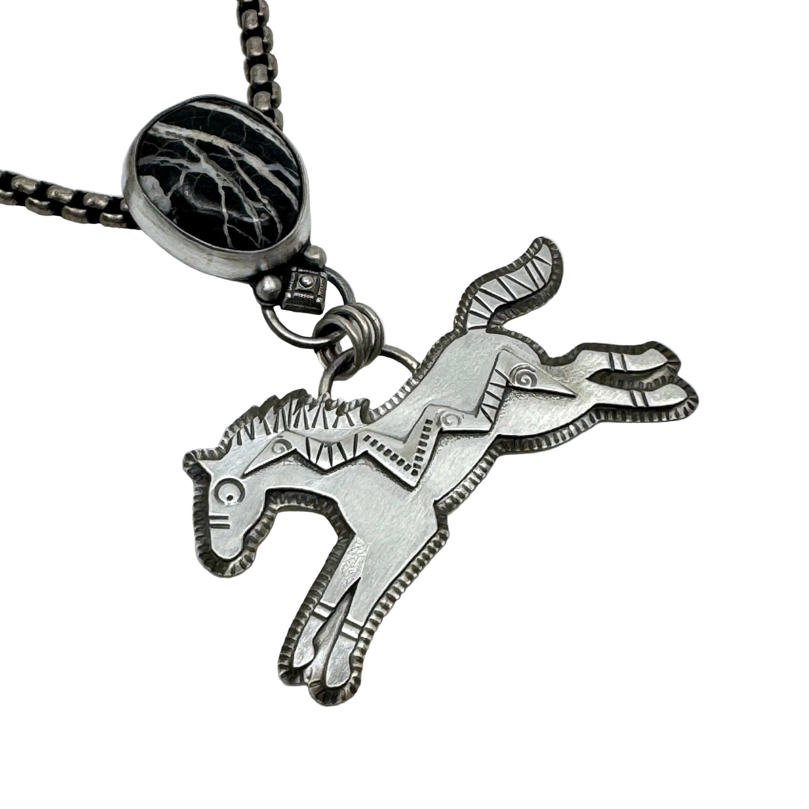 Silver horse pendant on a chain with a zebra-patterned accent stone against a white background
